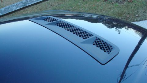 2004 Ford Crown Victoria - A gray vent is visible on the glossy black hood of a car, with a watermark at the bottom right.