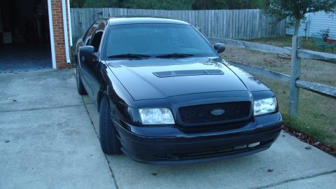 2004 Ford Crown Victoria - A black Ford Crown Victoria is parked in a driveway, a modified hood with a scoop.
