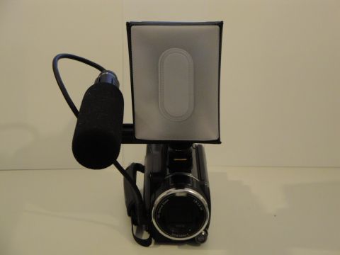 1993 Ford Taurus - A camcorder is shown from the front, equipped with a directional microphone and a light panel.