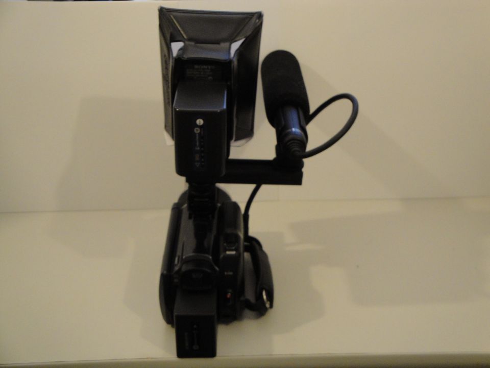Video camera with external microphone and light attachment, viewed from the side