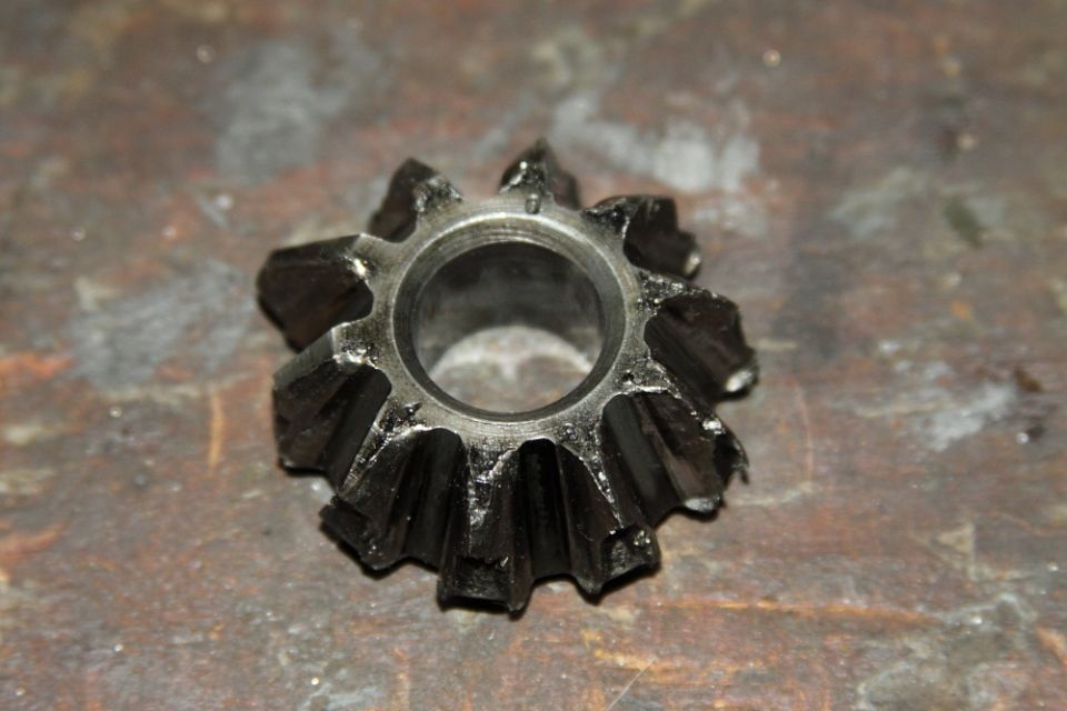 Broken spider gear with chipped teeth on a textured surface