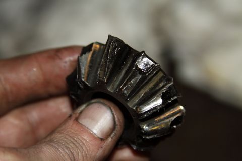 2004 Jeep TJ - A damaged differential spider gear is held by a person's fingers.