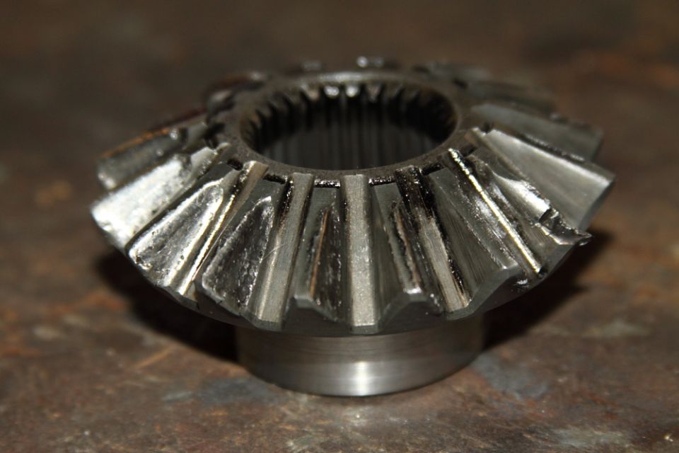 Close-up of a metal differential spider gear with worn teeth