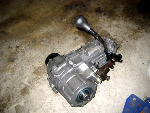 1996 Ford Bronco - A vehicle transfer case with its shifter lever is shown resting on a concrete surface.