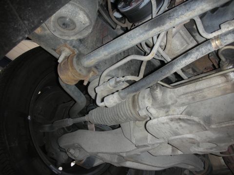 2004 Ford Crown Victoria - Close-up of vehicle undercarriage, focusing on sway bar and steering system parts.