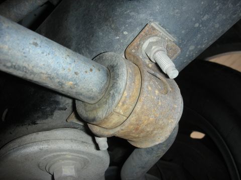 2004 Ford Crown Victoria - This photo shows a close-up of a rusty sway bar mount on a vehicle's rear suspension system.
