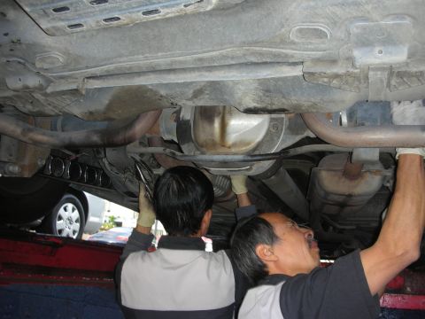 2004 Ford Crown Victoria - Mechanics install a swaybar on the undercarriage of a 2004 Ford Crown Victoria.