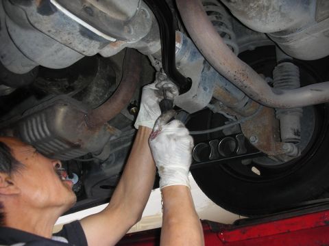 2004 Ford Crown Victoria - Mechanic installing an aftermarket swaybar on the rear suspension of a vehicle.
