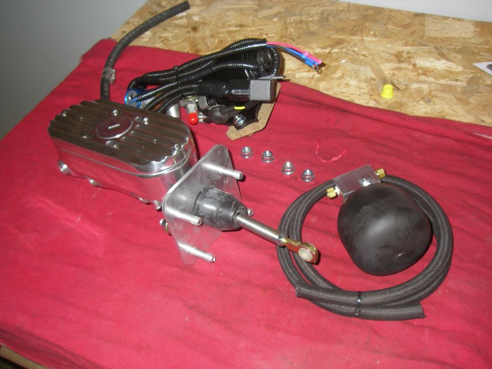 Chrome brake booster and master cylinder with black hoses and electrical connectors on a red cloth