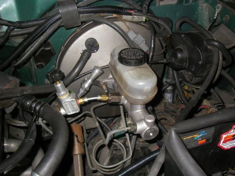 1990 Ford Bronco - Close-up view of the brake booster and master cylinder assembly, showing various hoses and lines connected to the components.