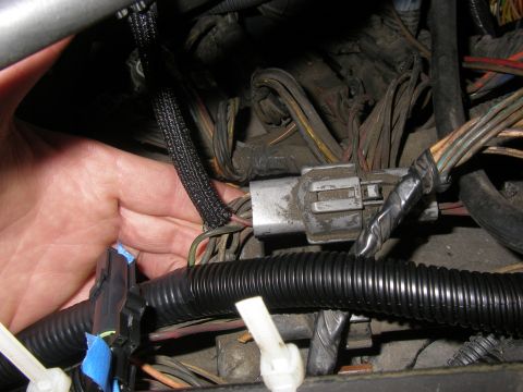 1990 Ford Bronco - A hand reaches for a connector in a complex engine wiring harness.