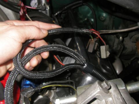 1990 Ford Bronco - Close-up of an engine wiring harness being held by a hand, showing electrical connections.