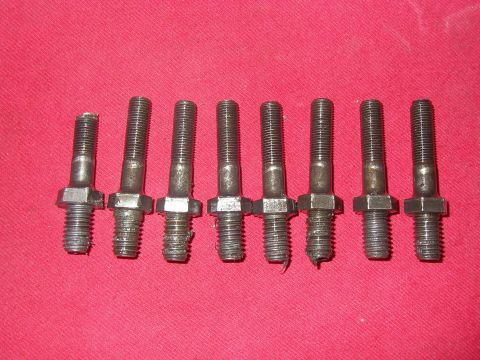 1990 Ford Bronco - Eight used rocker arm studs laid out in a row on a red cloth background, each with a coarse-thread lower end, a hex wrenching flat mid-shaf…