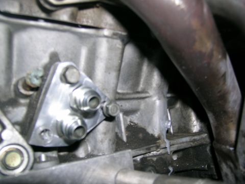 1995 Ford Probe - Aftermarket oil cooler adapter plate mounted to an engine block, with plumbing fittings visible.