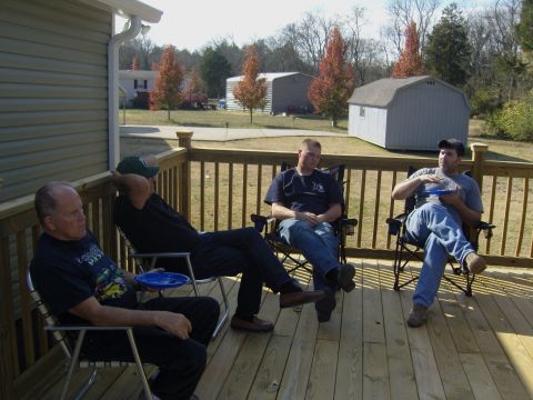 2007 Ford Mustang - Men relax on a deck during an outdoor gathering, with houses and sheds in the background.