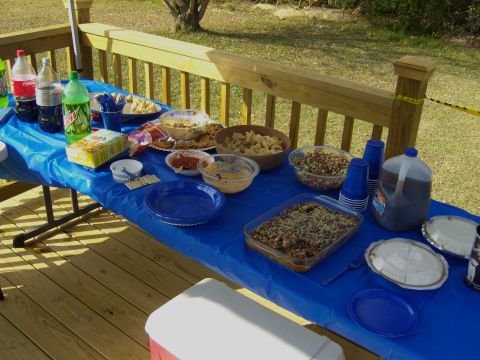 2007 Ford Mustang - A spread of food and beverages is laid out on a table covered with a blue tablecloth on an outdoor deck.