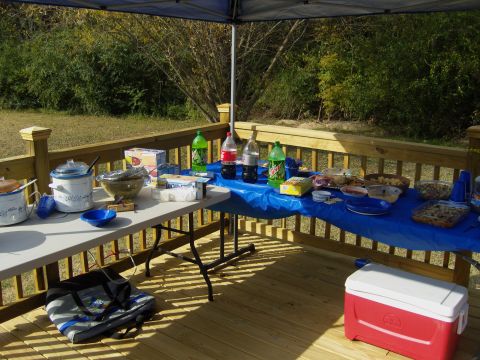 2007 Ford Mustang - A spread of food and drinks is laid out on tables on a wooden deck, suggesting an outdoor event.