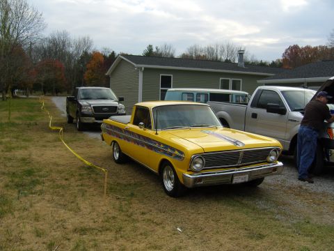 2007 Ford Mustang - A vintage yellow pickup truck is parked in a yard with other vehicles and a house in the background.