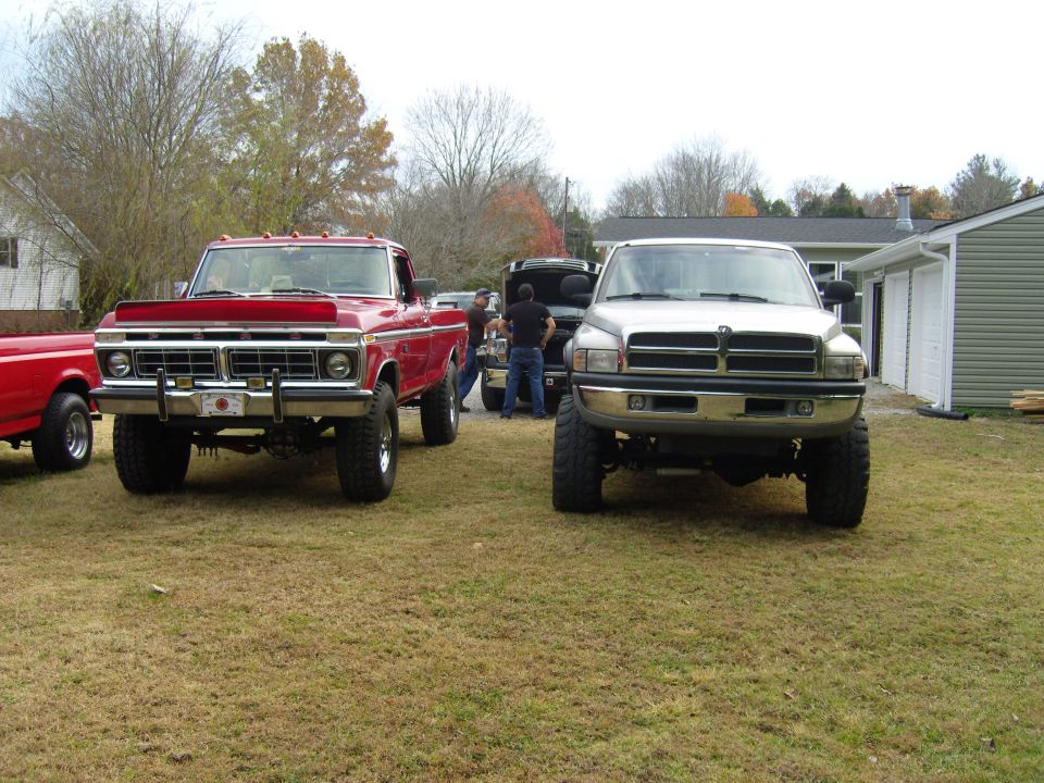 Red 1973 Ford F-Series truck and silver Dodge Ram truck parked on grass