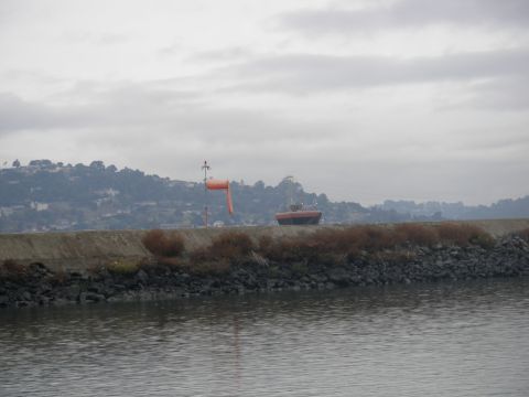 1991 Ford Bronco - A boat and a windsock are visible on a breakwater with a hilly landscape in the background.