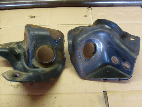 1986 Ford Bronco - Two metal brackets, likely for a vehicle suspension, are shown on a cardboard surface.