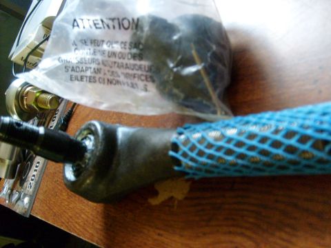 1986 Ford Bronco - A close-up of a vehicle tie rod end, partially covered by protective netting and a warning bag.