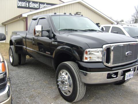 2007 Ford Mustang - Black 2007 Ford F-350 Super Duty dually truck parked in front of a building with a sign that reads "Bean's Diesel Performance".