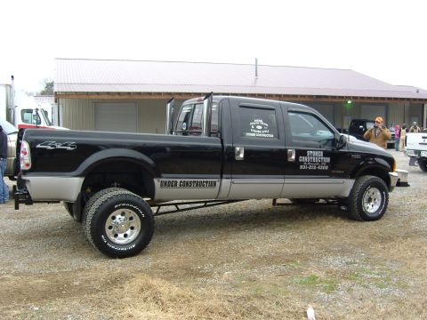2007 Ford Mustang - A black and silver crew cab pickup truck with dual rear wheels is parked outdoors with "UNDER CONSTRUCTION" written on its side.