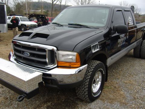 2007 Ford Mustang - Black Ford F-350 Super Duty dually truck with aftermarket hood scoop and toolbox bumper.