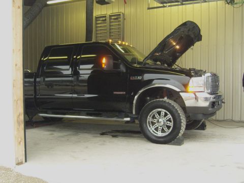 2007 Ford Mustang - A black pickup truck is parked inside a garage with its hood open.