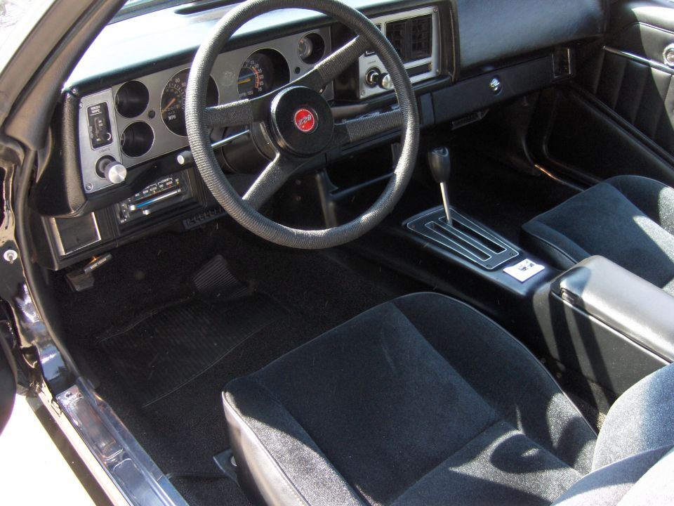 1979 Chevrolet Camaro interior with black cloth seats, a four-spoke steering wheel, and a center console with an automatic shifter
