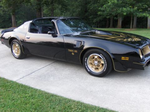 1979 Chevrolet Camaro - This 1979 Pontiac Trans Am features gold decals and wheels, with a distinctive hood scoop.