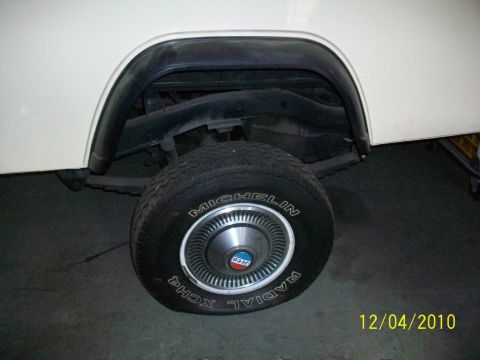 1986 Jeep Wagoneer - The rear wheel assembly of a Jeep is shown, including the tire, hubcap, fender flare, and suspension components.