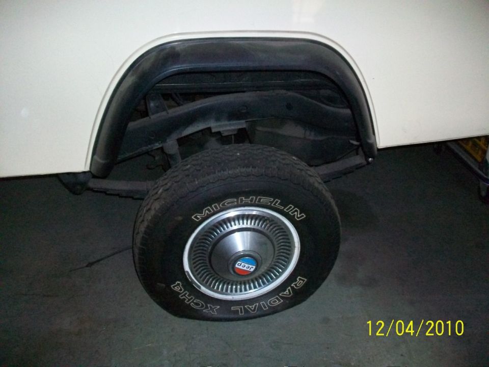 Close-up of a Jeep's rear wheel with a Michelin Radial XCH4 tire and a hubcap with a Jeep logo