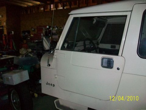 1986 Jeep Wagoneer - The side view of a white Jeep shows its door and paneling, with the brand name clearly visible.