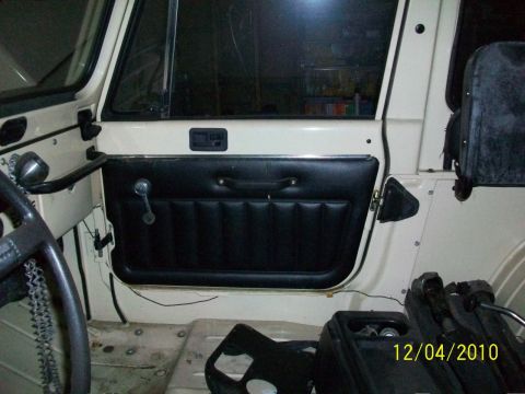 1986 Jeep Wagoneer - The interior of a Jeep shows a black door panel with a chrome window crank and handle. A date stamp is visible in the corner.