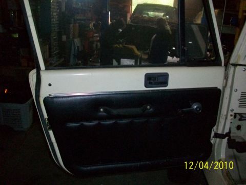 1986 Jeep Wagoneer - Interior view of a white Jeep door with black paneling and a chrome window crank.