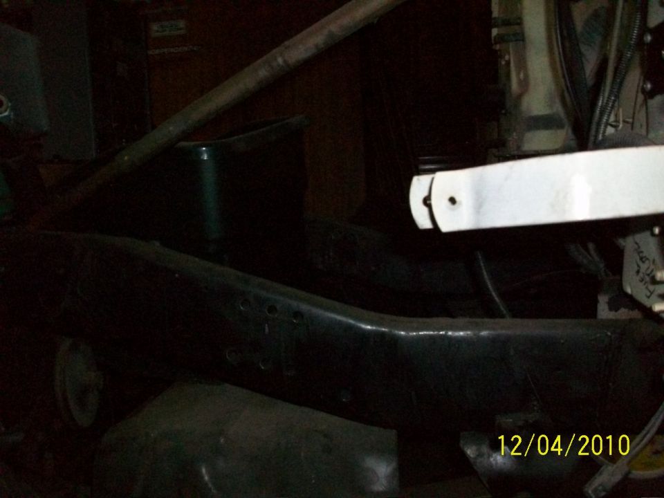 Close-up of a dark metal vehicle frame with some white metal parts and wiring visible. Date stamp reads 12/04/2010