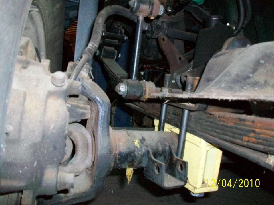 Close-up of front axle, leaf spring, and shock absorber assembly