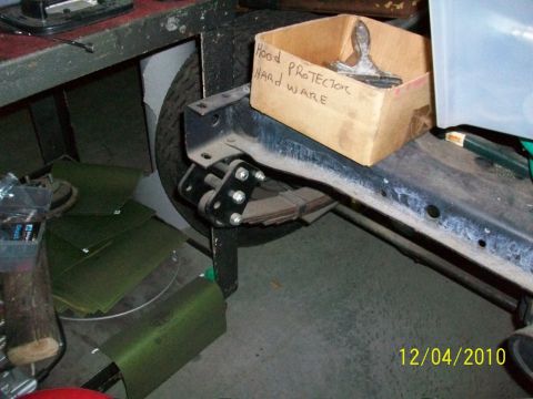 1986 Jeep Wagoneer - A box of hood protector hardware sits on the frame of a vehicle next to a tire.