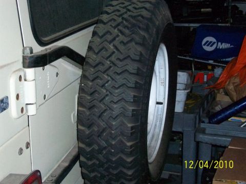 1986 Jeep Wagoneer - Close-up of a spare tire mounted on the rear door of a white vehicle, with a date stamp of 12/04/2010.