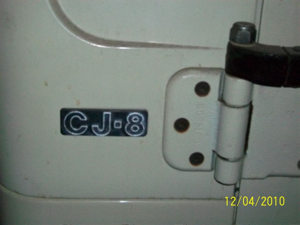 CJ-8 badge on a white Jeep door, next to a door hinge