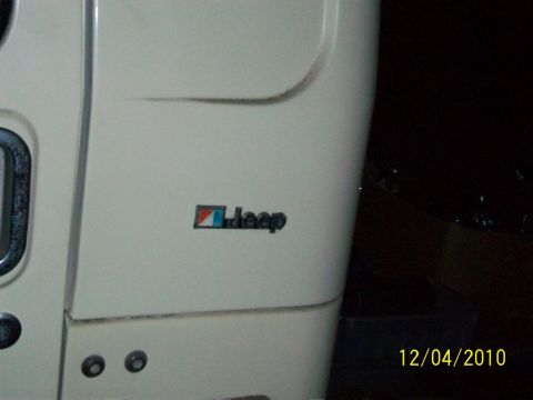 1986 Jeep Wagoneer - A Jeep emblem is visible on the side panel of a white vehicle, with a date stamp in the corner.