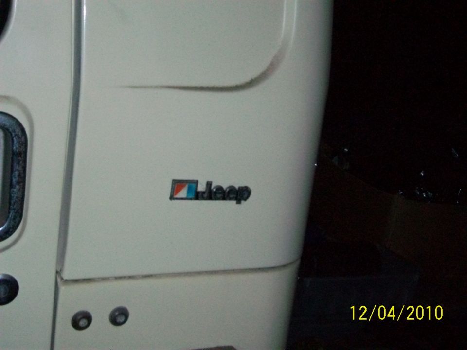 Close-up of a Jeep emblem on a white vehicle panel. Date stamp shows 12/04/2010