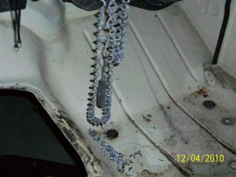 1986 Jeep Wagoneer - The engine bay of a vehicle shows a coiled metal chain and signs of rust and wear.