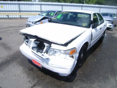 2003 Ford Crown Victoria - This white sedan has significant damage to its front end, with the hood crumpled and open.