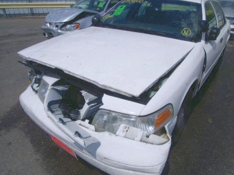 2003 Ford Crown Victoria - Front end of a wrecked 2003 Ford Crown Victoria, showing extensive damage to the hood and bumper.