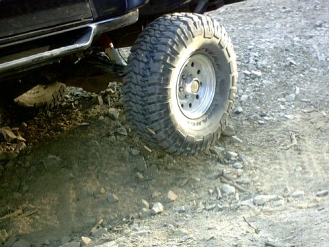 1995 Ford Bronco - This photo shows a close-up of a vehicle's off-road tire and wheel on a rocky trail.