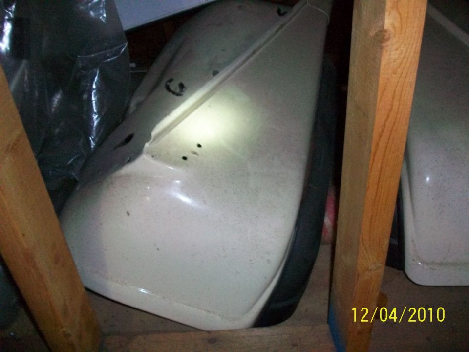 White vehicle fender with black trim and tire, viewed from the side in storage