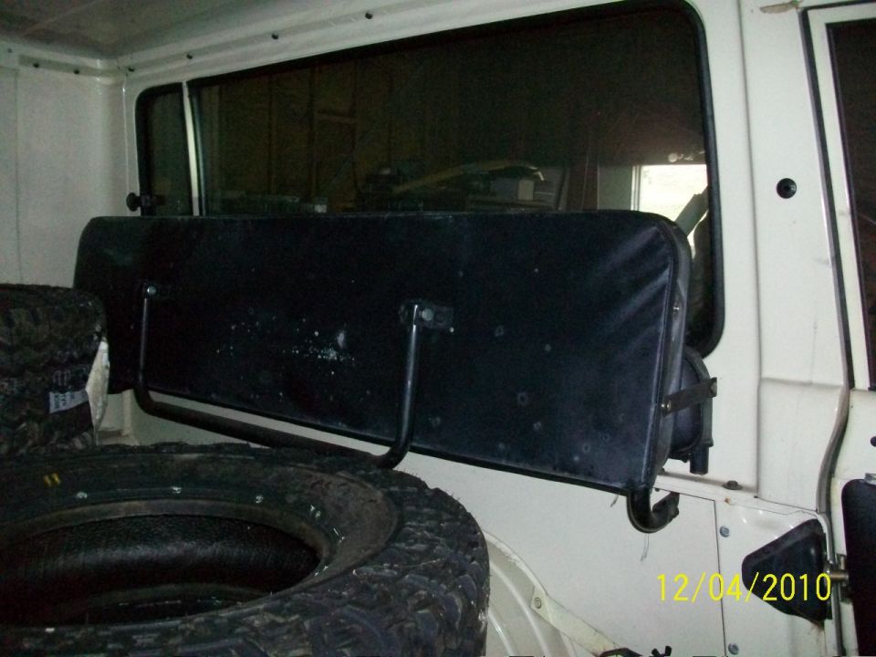 Spare tire and black rear seat inside a white vehicle